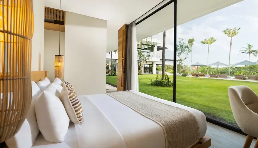 Bedroom with a king-sized bed and a large glass door opening to a green lawn at Villa Arita