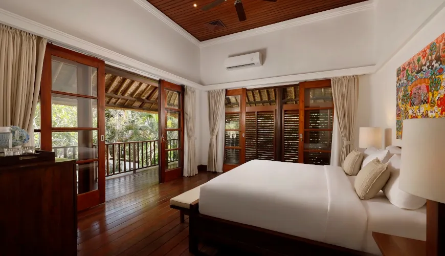 Luxurious bedroom with a high-pitched wooden ceiling and a private balcony overlooking a garden