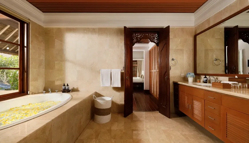 Opulent Balinese bathroom with marble floor, soaking tub, and carved wooden doors at Villa Avaya