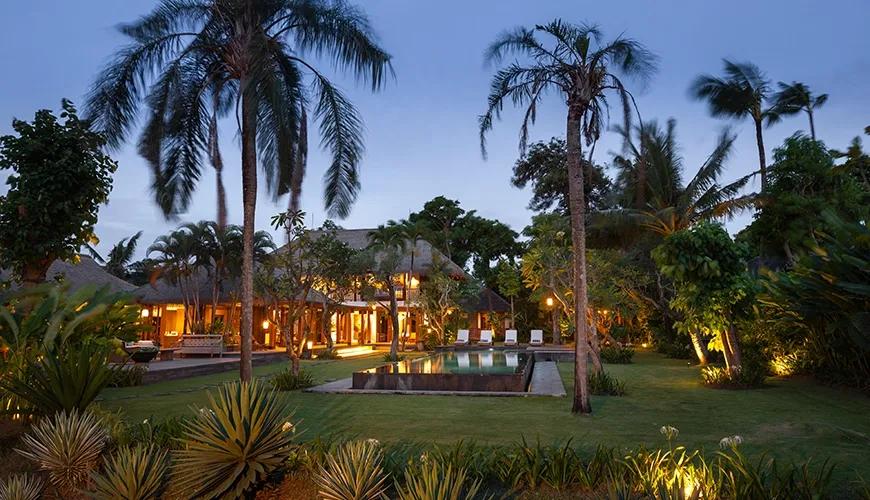 Atmospheric night shot of a tropical villa pool with illuminated garden paths and comfortable outdoor seating at Villa Bangkuang