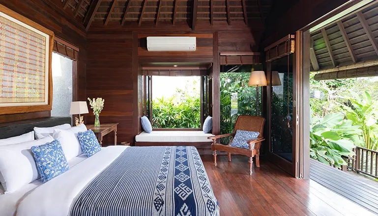 Cozy villa bedroom with a private balcony, a comfortable window sofa, and tasteful blue and wood decor at Villa Bangkuang