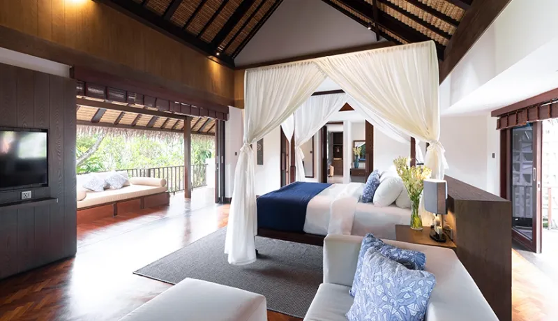 Elegant master bedroom featuring a four-poster bed with canopy, a large sofa, and beautiful wooden accents at Villa Bangkuang