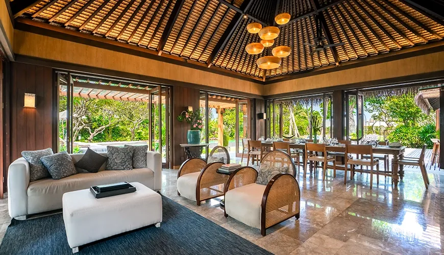 Luxury villa open-plan living room featuring comfortable seating, a dining table, and beautiful thatched ceiling at Villa Bangkuang