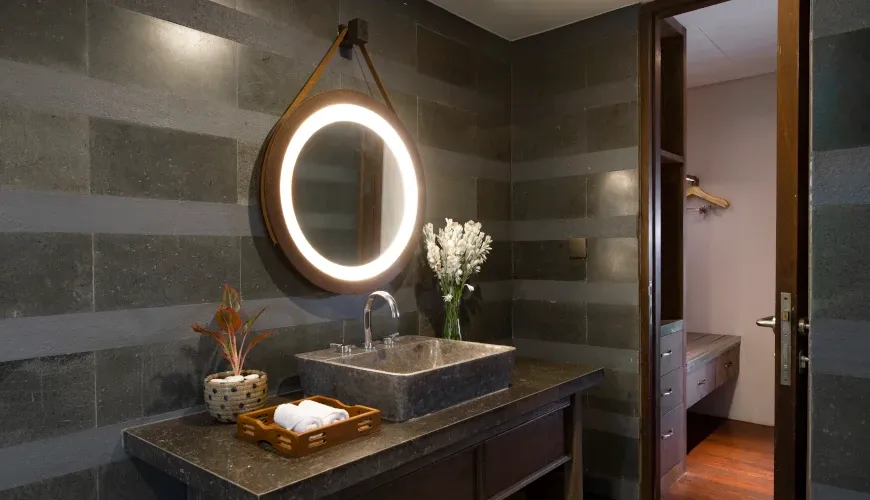 Modern Balinese bathroom with stone sink and illuminated mirror at Villa Bangkuang