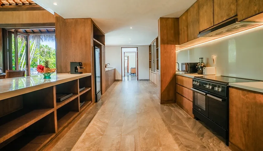 Modern villa kitchen with warm wooden cabinetry, stone countertops, and a full size professional range at Villa Bangkuang