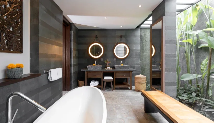 Spacious bathroom with round backlit mirrors and stone sinks at Villa Bangkuang