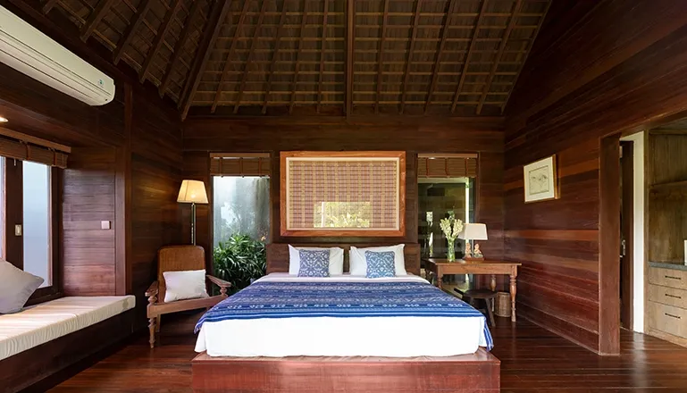 Spacious bedroom with a king bed, featuring elegant blue, white, and wooden accents and a vaulted ceiling at Villa Bangkuang