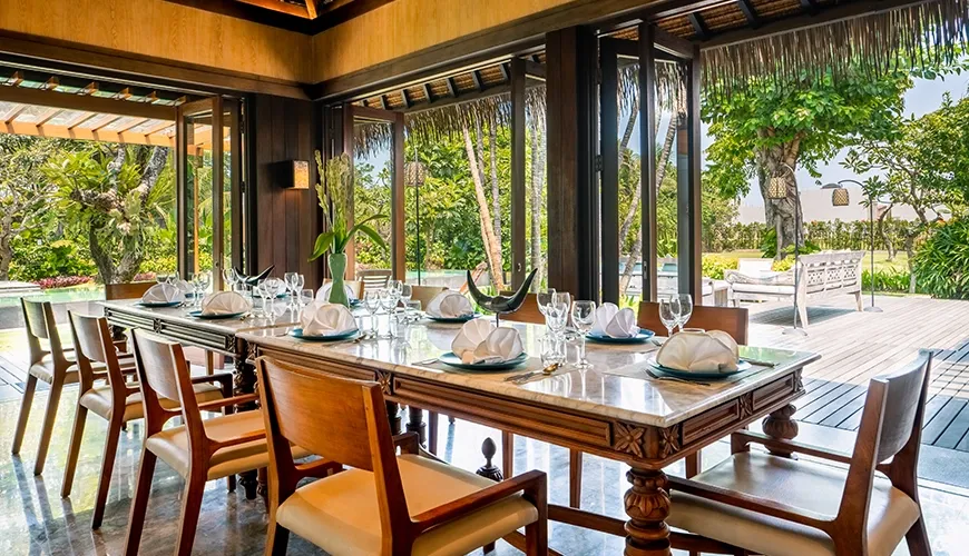 Tropical villa dining area overlooking a serene swimming pool and lush outdoor garden at Villa Bangkuang