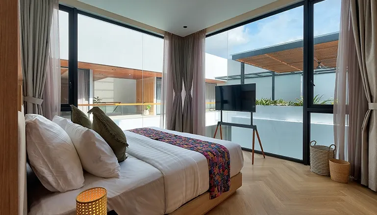 Bright bedroom with large windows a comfortable bed and TV at Villa Brandon