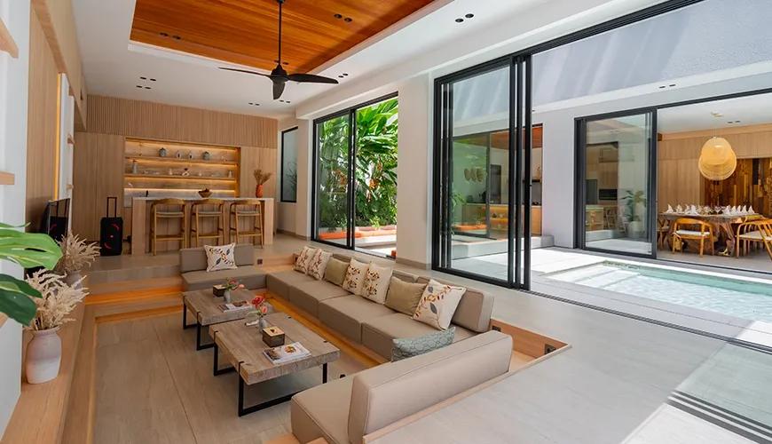Contemporary open plan living room featuring wood ceilings and large sliding glass doors leading to a pool at Villa Brandon