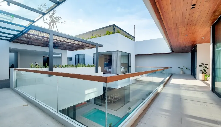 Modern villa balcony with glass railing overlooking the pool at Villa Brandon