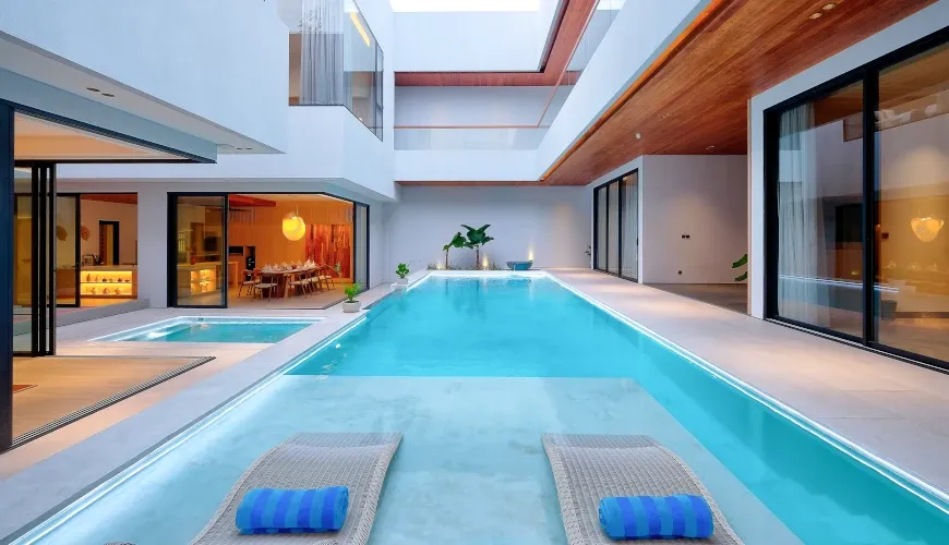 Modern villa indoor pool with lounge chairs and glass walls at Villa Brandon