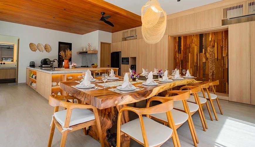 Spacious kitchen area with integrated appliances and a long wooden dining table under accent lighting at Villa Brandon