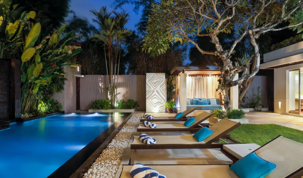 Lush tropical garden with illuminated pool and sunbeds at Villa Camellia