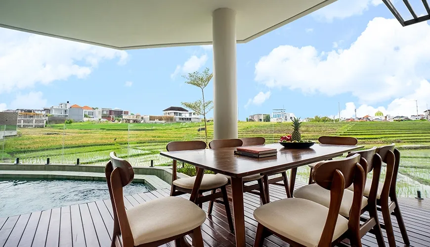 Al fresco dining space on a wooden deck next to the pool with amazing panoramic rice field views at Villa Chanthira Luxe