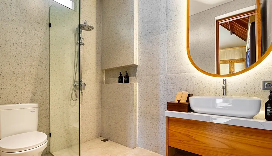 Contemporary guest bathroom with beautiful terrazzo walls, minimalist toilet, and integrated shower niche shelving at Villa Chanthira Luxe