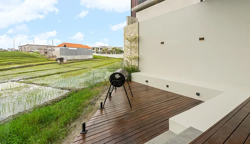 Covered outdoor grilling area with a black charcoal barbecue on the hardwood deck patio at Villa Chanthira Luxe