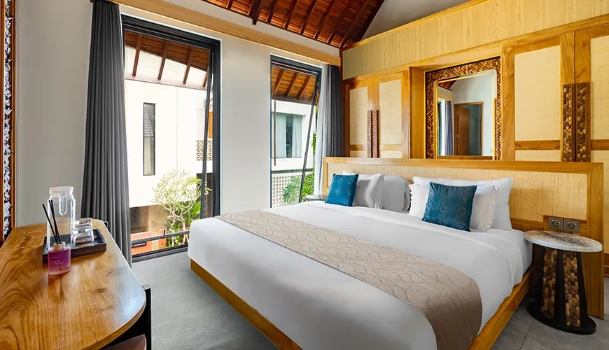 Luxury king size bedroom with high windows, rattan furniture details, and a striking wooden arch roof at Villa Chanthira Luxe