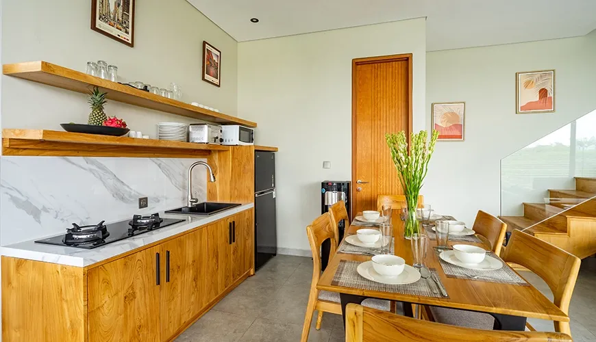 Open plan kitchen and dining area featuring marble countertop, wooden cabinets, and modern appliances at Villa Chanthira Luxe