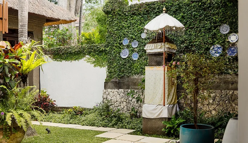 Tranquil villa garden with lush greenery, stone pathway, and decorative plates at Villa Danis