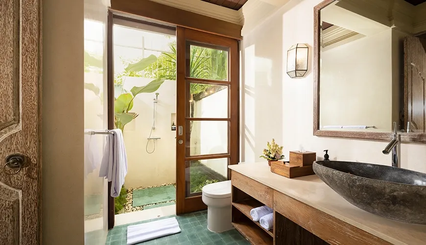 Beautiful stone sink and floating wooden vanity with an incredible open-air outdoor shower area perfect for guests at Villa Grasshopper