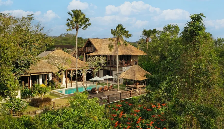 Luxurious tropical villa rental surrounded by vibrant green jungle foliage and beautiful orange flowers at Villa Grasshopper