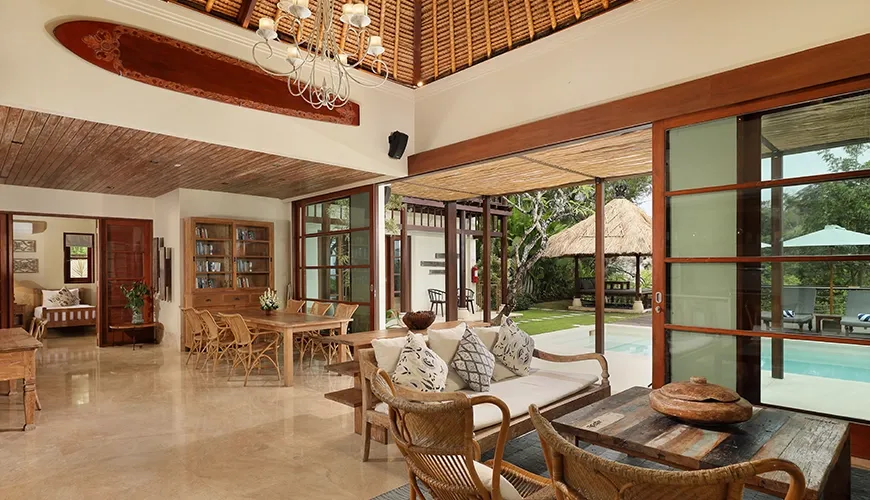 Spacious open plan villa living room featuring rattan furniture, high thatched ceiling, and poolside access at Villa Grasshopper