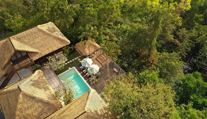 Stunning aerial drone view of a private thatched roof villa estate completely hidden within dense tropical rainforest at Villa Grasshopper