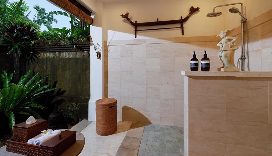 Inviting outdoor bathroom featuring natural stone tiles, decorative sculptures, and lush tropical greenery at Villa Inka