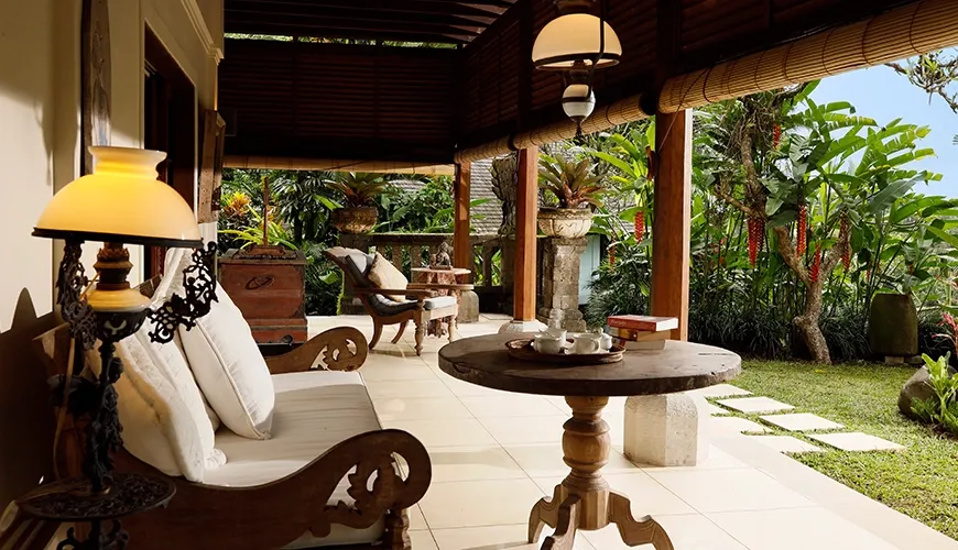 Peaceful villa terrace with a wooden sofa, ornate coffee table, and comfortable seating surrounded by lush foliage at Villa Inka