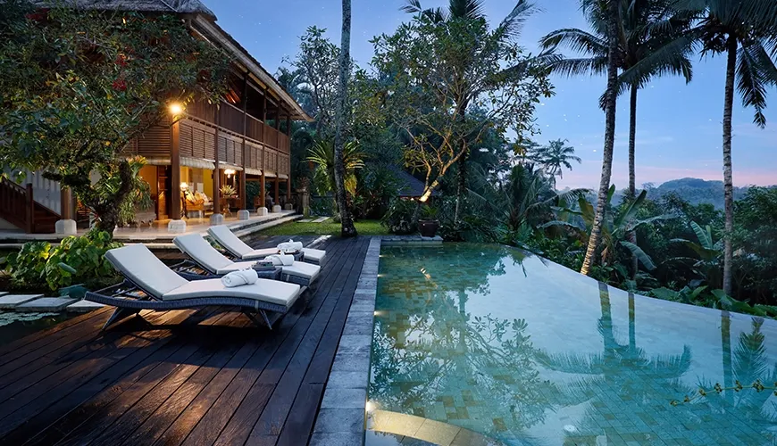 Stunning tropical villa with a luxurious infinity pool surrounded by palm trees during the peaceful blue hour at Villa Inka