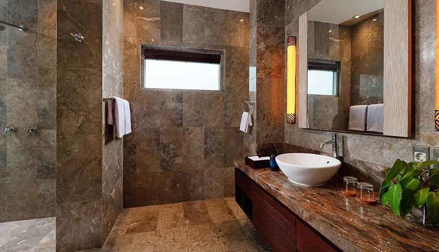 Luxurious and modern bathroom with textured stone walls a large mirror and walk in shower at Villa Jamalu
