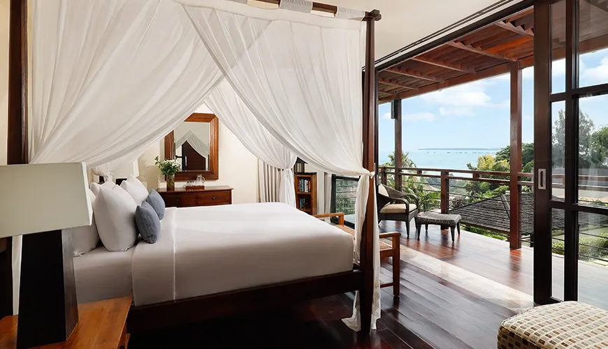 Luxurious bedroom in a private villa featuring a wooden four-poster bed with white curtains at Villa Jamalu