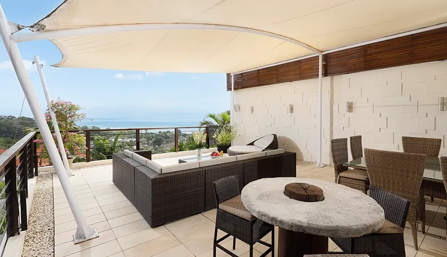 Sunny rooftop terrace with outdoor seating and beautiful panoramic views of the ocean at Villa Jamalu