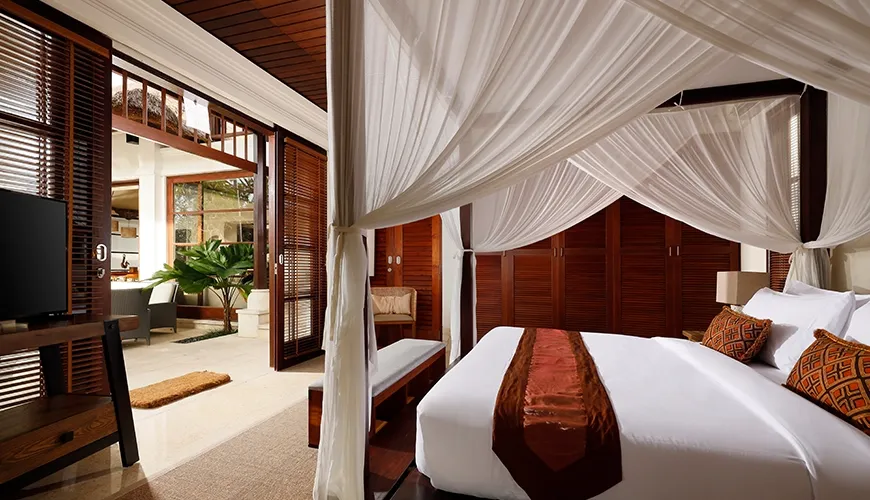 Beautiful bedroom suite features an elegant canopy bed, a television, and a private outdoor living area at Villa Ken
