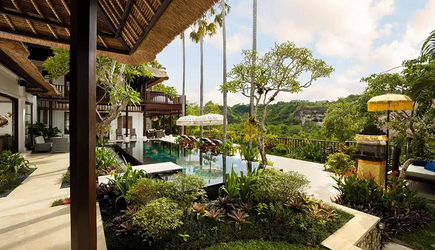 Infinity pool with sun loungers overlooking lush green valley at Villa Ken