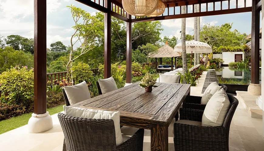 Outdoor dining lounge with wooden table and lush garden views at Villa Ken