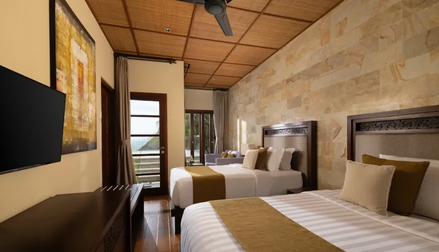 Cozy bedroom with twin beds and a rustic stone accent wall at Naga Sutra Villa
