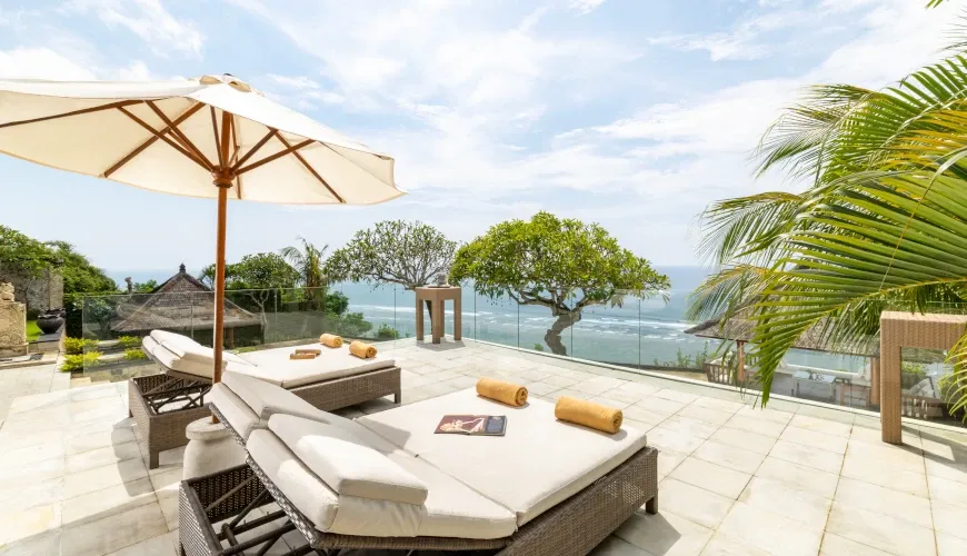Outdoor terrace with lounge chairs and a stunning ocean view at Naga Sutra Villa