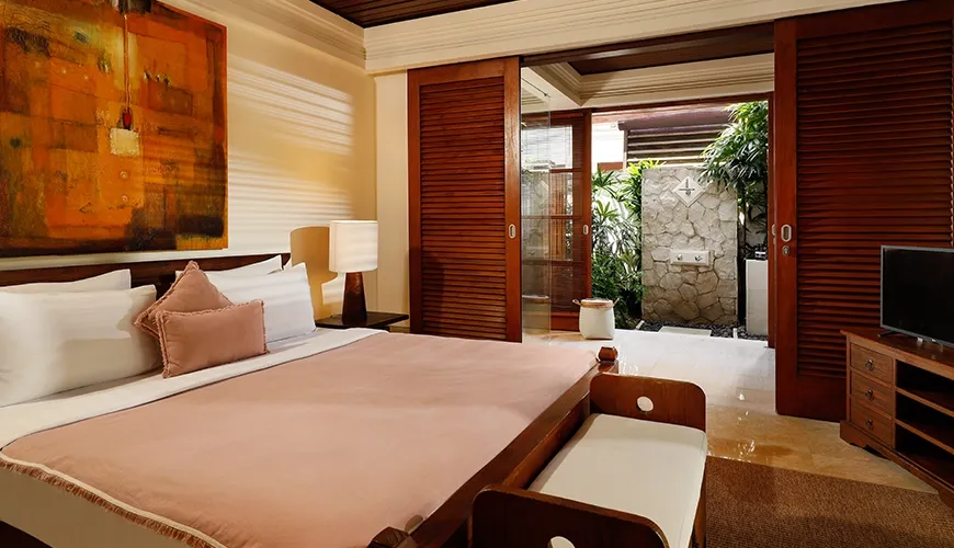 Inviting villa bedroom with a plush king bed and sliding doors leading to a private outdoor shower at Villa Nayra