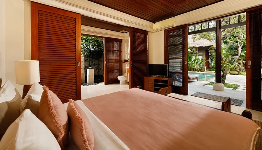 Spacious villa bedroom featuring a king-sized bed and direct access to a refreshing private pool at Villa Nayra