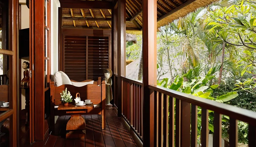 Tranquil villa balcony with handcrafted wooden furniture overlooking lush tropical foliage and gardens at Villa Nayra