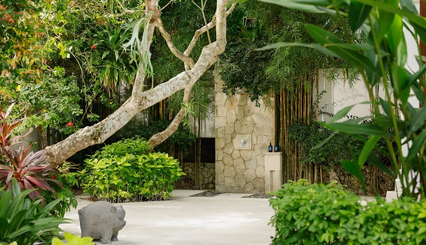 Secluded outdoor shower surrounded by lush tropical greenery and a stylish natural stone wall at Villa Ohm