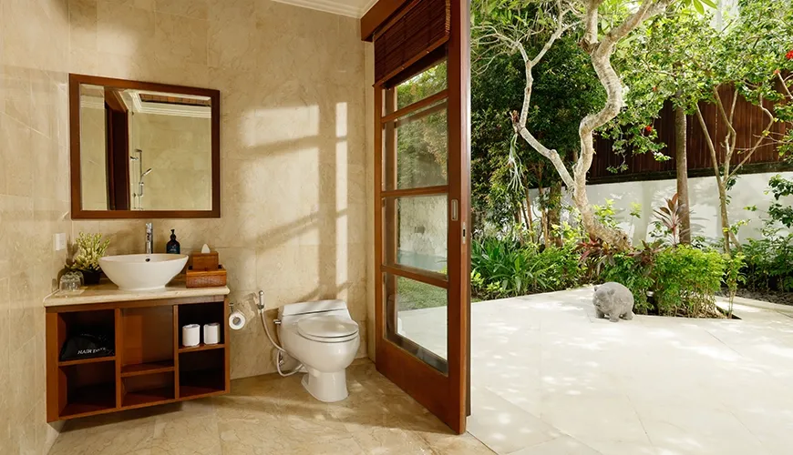 Stunning indoor-outdoor guest bathroom with marble stone, dark vanity, and large door opening to a private garden at Villa Ohm