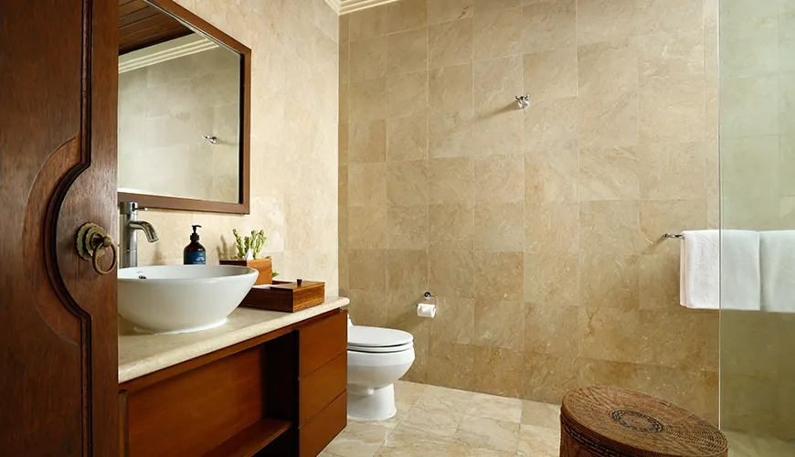 Upscale guest bathroom featuring light marble stone walls, dark wood vanity, modern vessel sink, and glass shower at Villa Ohm