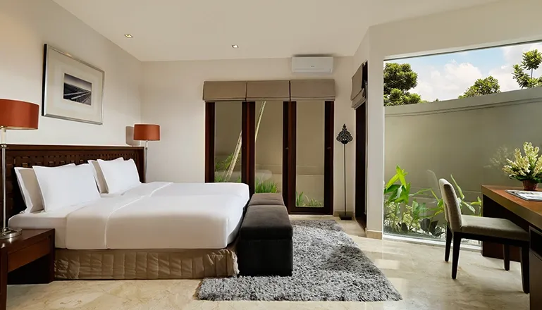 Bedroom with two twin beds grey bench and garden views at Villa Oshra