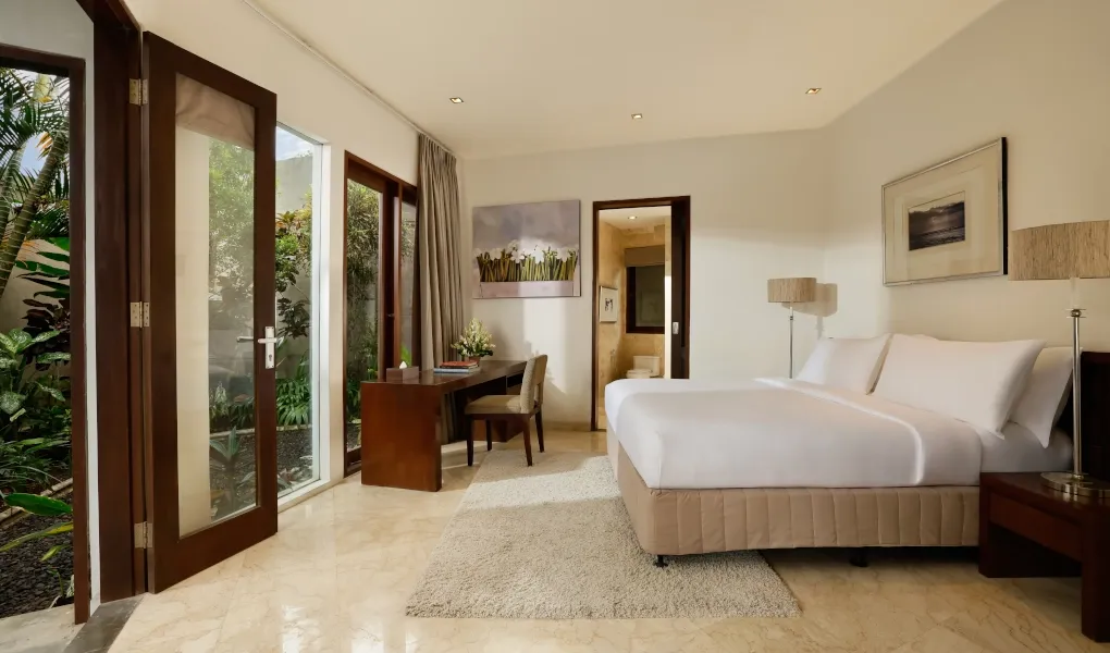 Bright bedroom with a large bed and doors opening to a garden at Villa Oshra