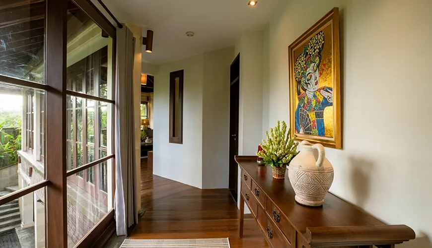 Beautifully decorated villa hallway with a wooden console table and a vibrant painting at Villa Pulung Jimbaran