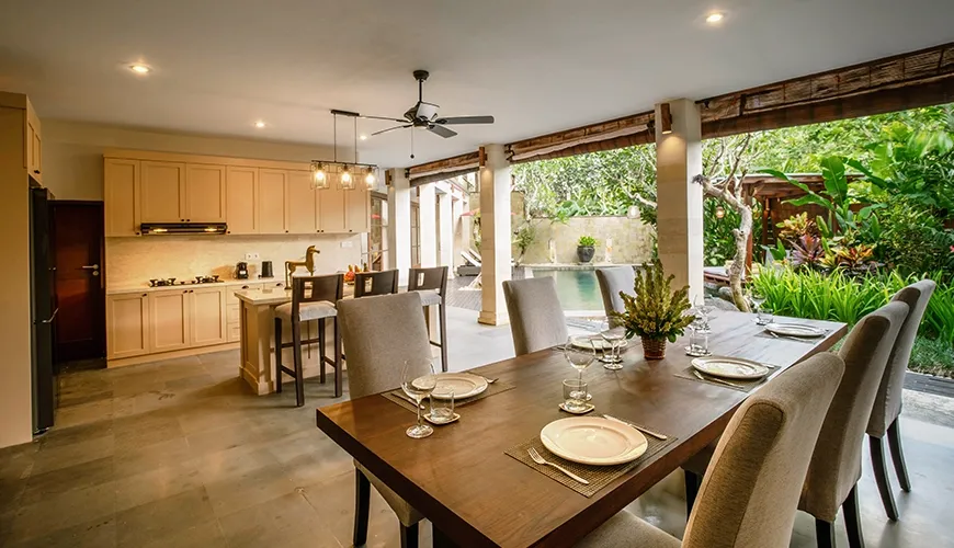 Spacious open-plan villa dining area with a wooden table, chairs, and modern kitchen at Villa Pulung Jimbaran