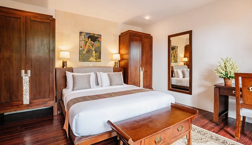 Spacious villa bedroom with two large wooden wardrobes, a king-sized bed, and a full-length mirror at Villa Pulung Jimbaran